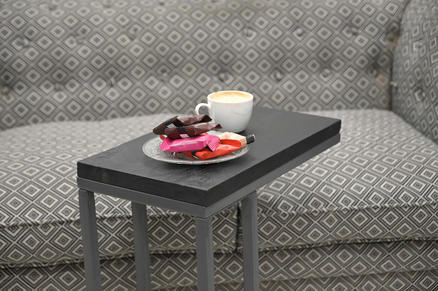 Moderner Beistelltisch aus Mangoholz vor grauem Sofa mit Kaffee und Snacks