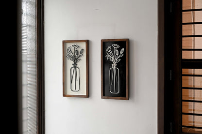 Zwei Wandbilder aus Mangoholz mit Blumenmotiv, dekorativ an weißer Wand aufgehängt.
